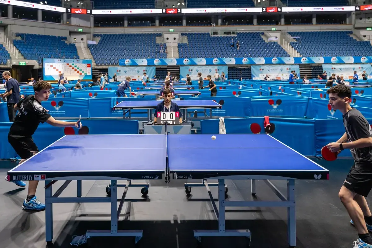 Table tennis players competing in a large indoor arena.