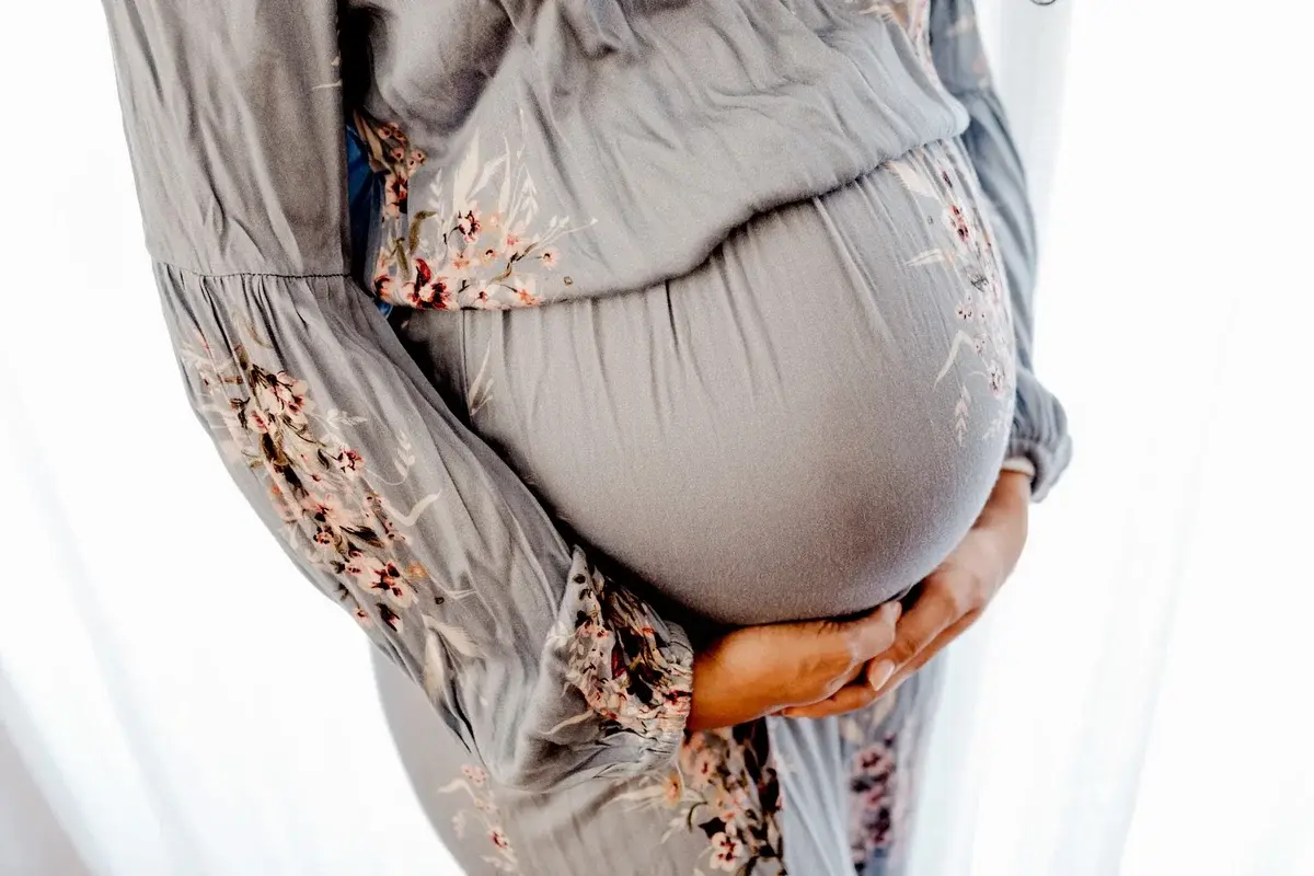 Overhead view of a pregnant woman holding her belly near a window.