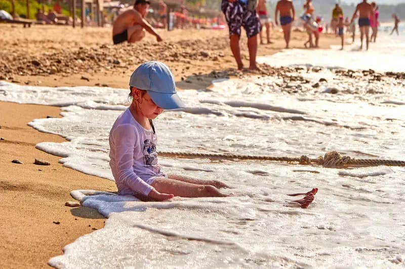 child sitting in foamy waves on beach