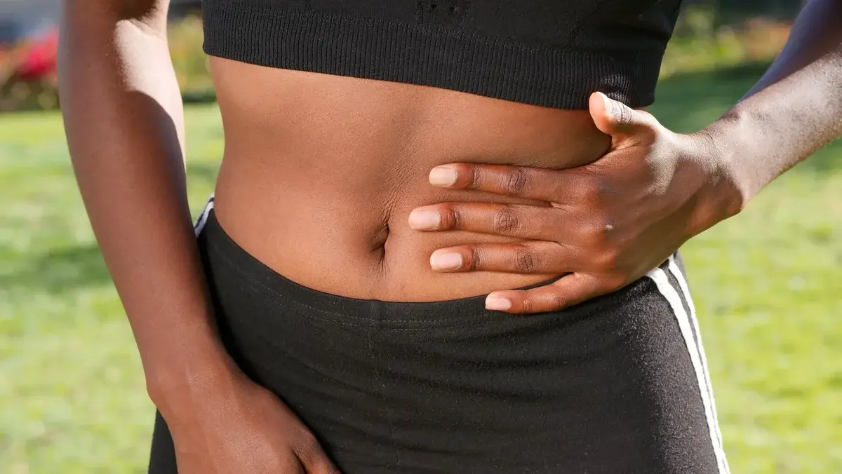 Close-up of a person holding their stomach outdoors.
