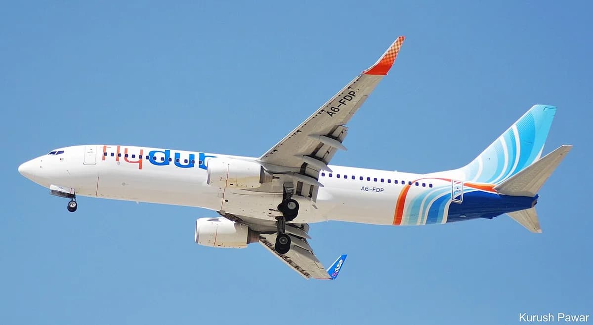 A FlyDubai Boeing 737 aircraft in flight against a blue sky.