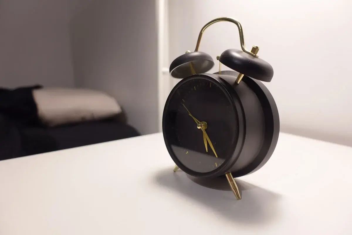 Black vintage-style alarm clock on a white bedside table