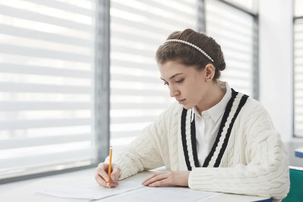 A student writing an exam in a bright classroom.
