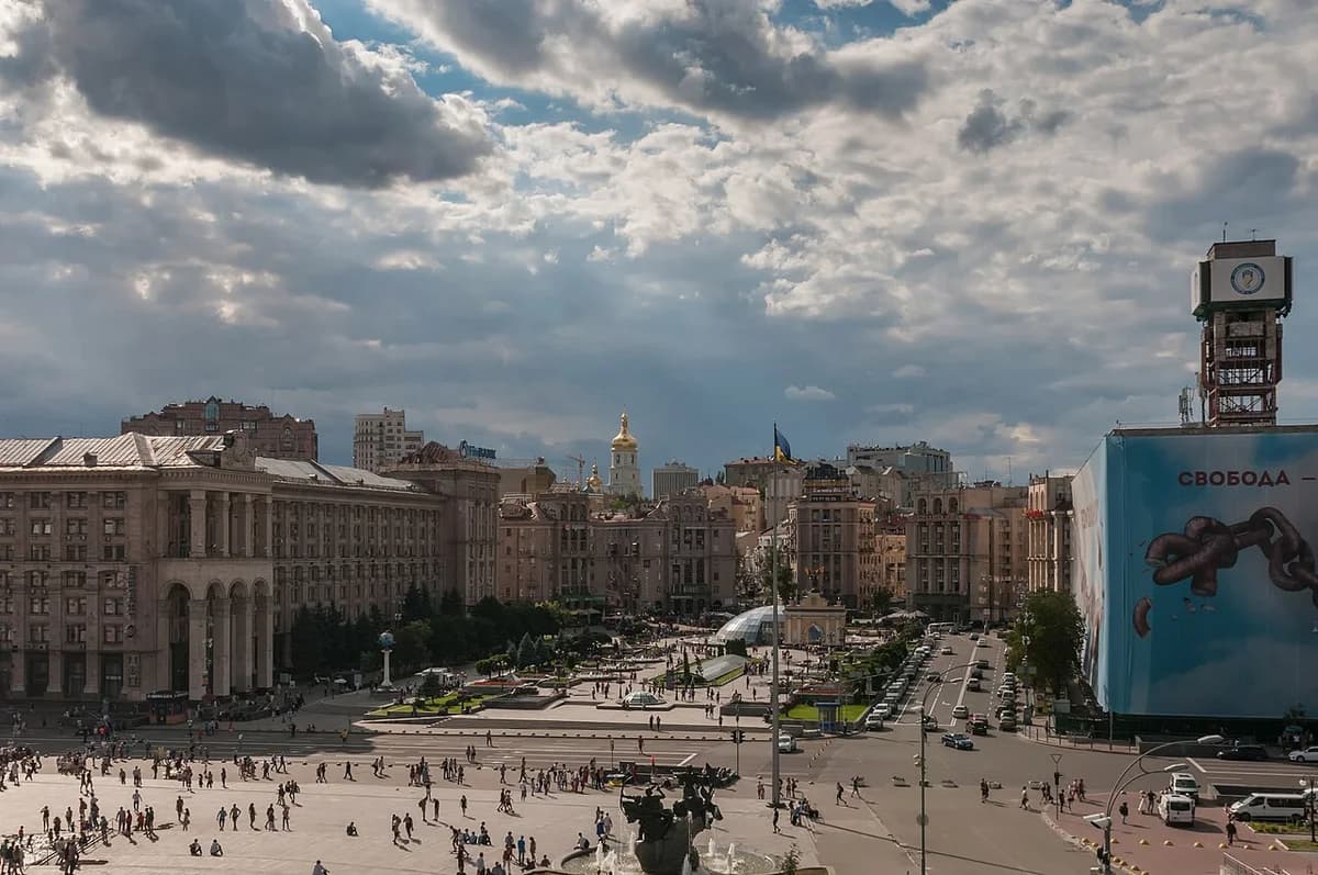 Wide view of Maidan Nezalezhnosti in Kyiv with people in the square and city buildings around it.