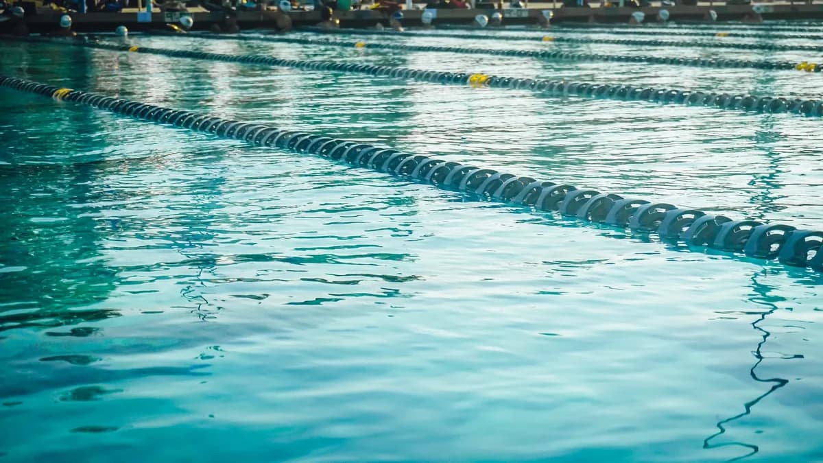 Calm outdoor swimming pool with lane dividers and blue water.