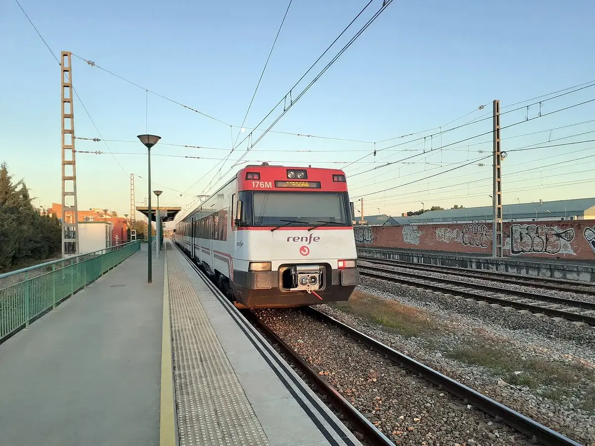 A Renfe commuter train stopped at a station platform.
