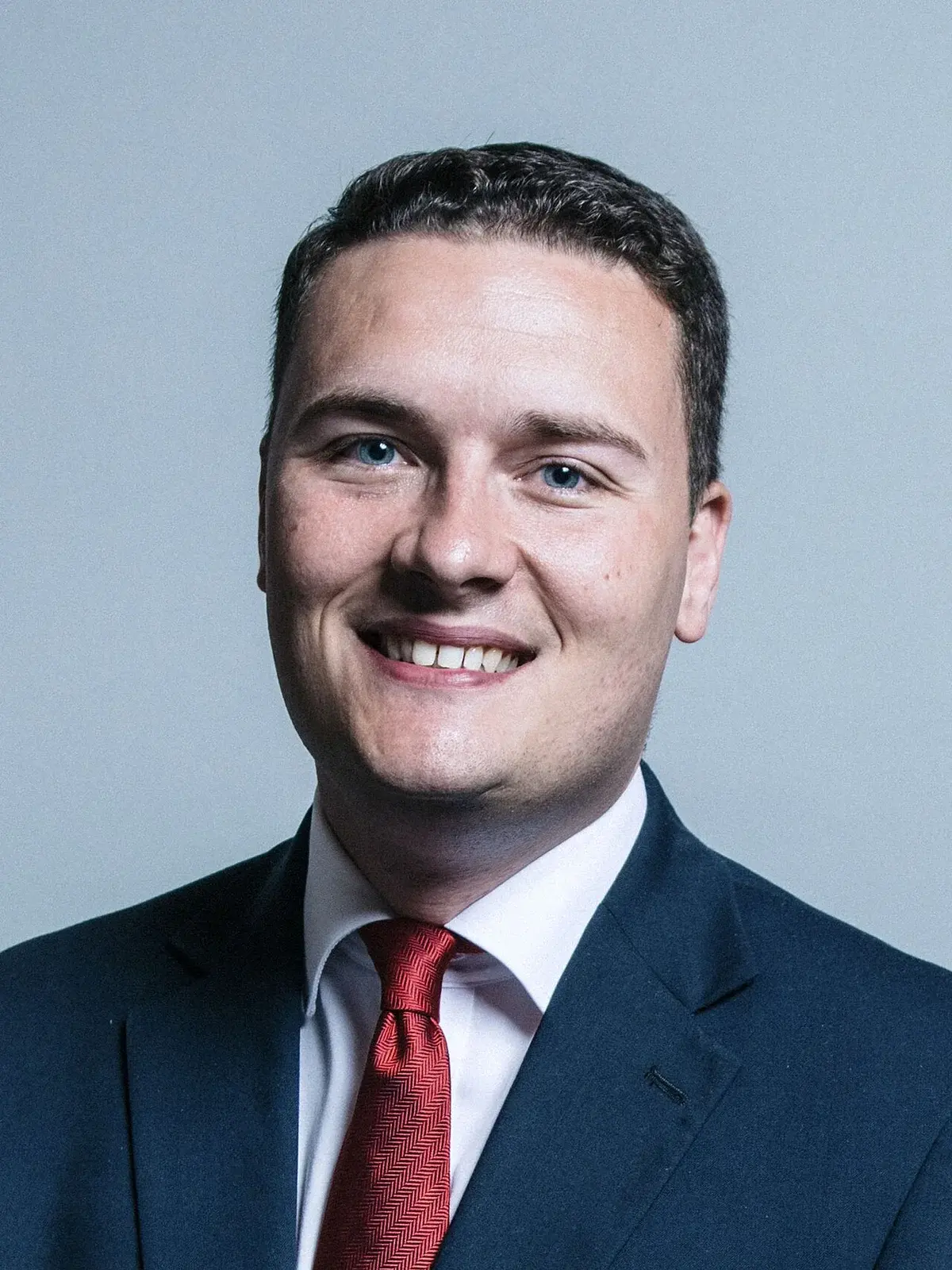 Studio portrait of Wes Streeting in a suit and red tie.