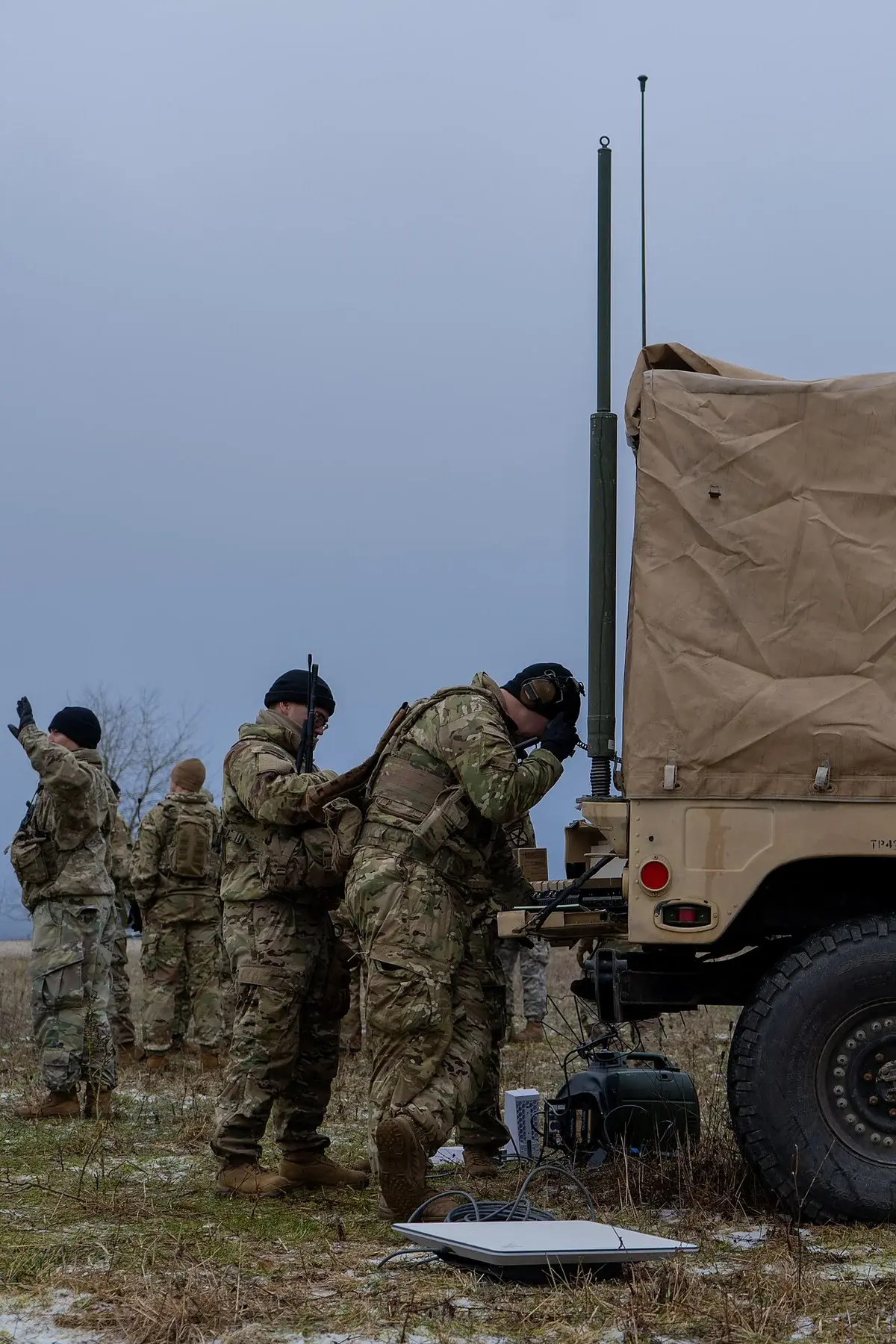 U.S. soldiers operate a Starshield communications setup beside a military vehicle in a field.