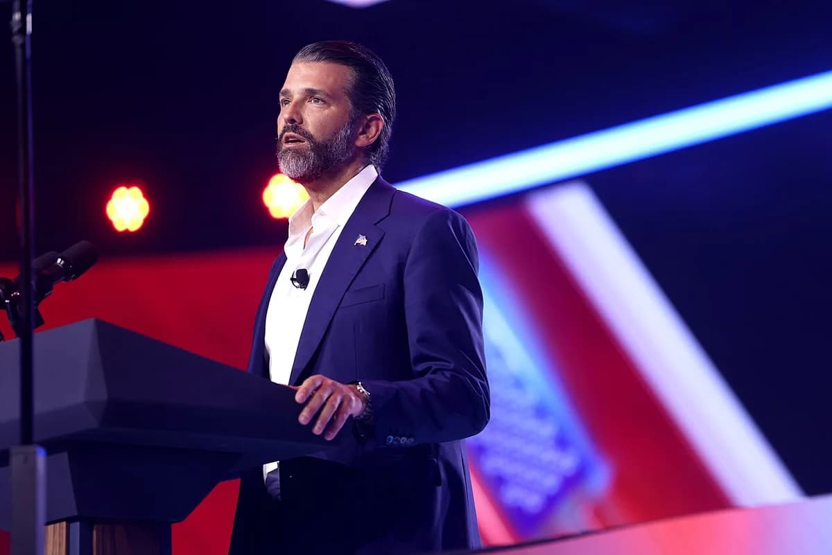 Donald Trump Jr. speaking at a podium during AmericaFest 2025.