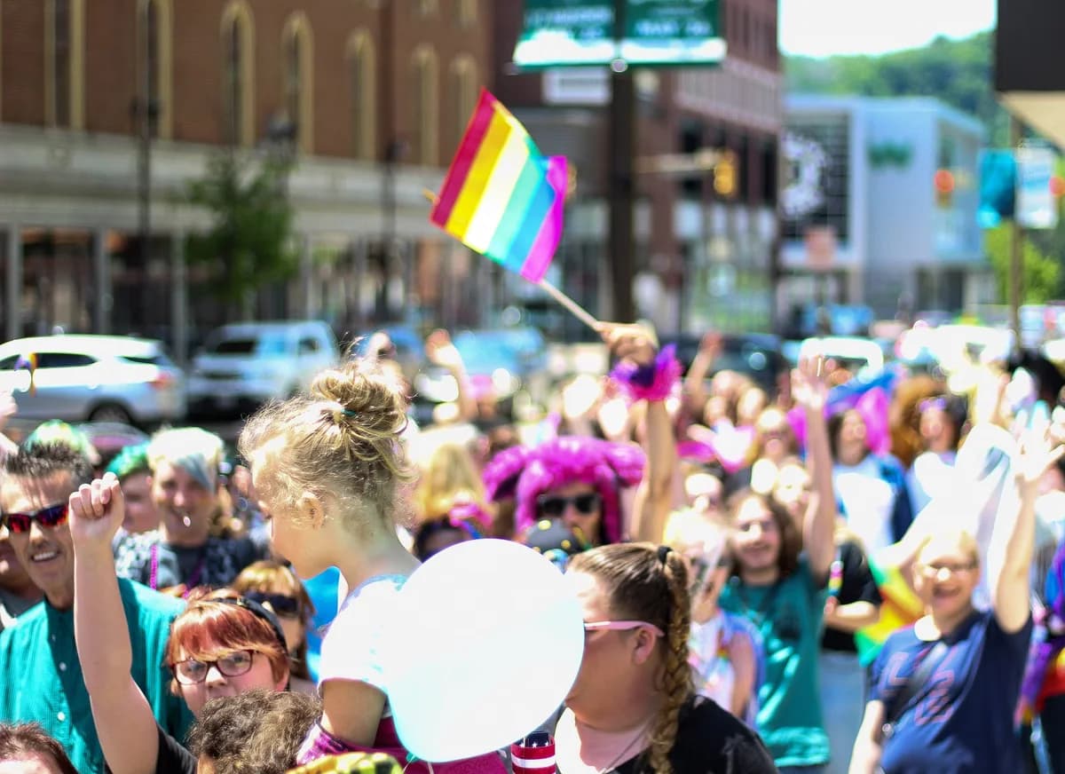 Crowd waving rainbow pride flags at a lively pride parade