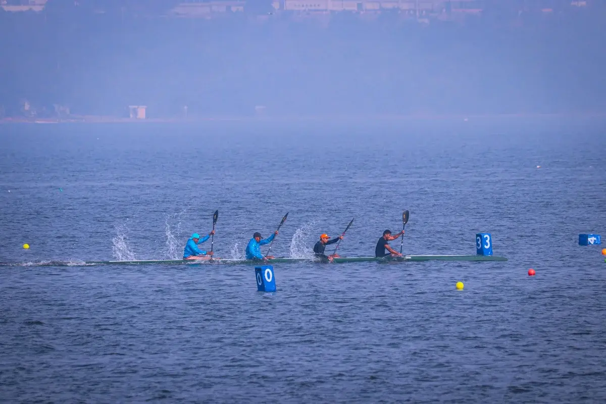 Four kayakers racing on a foggy lake.