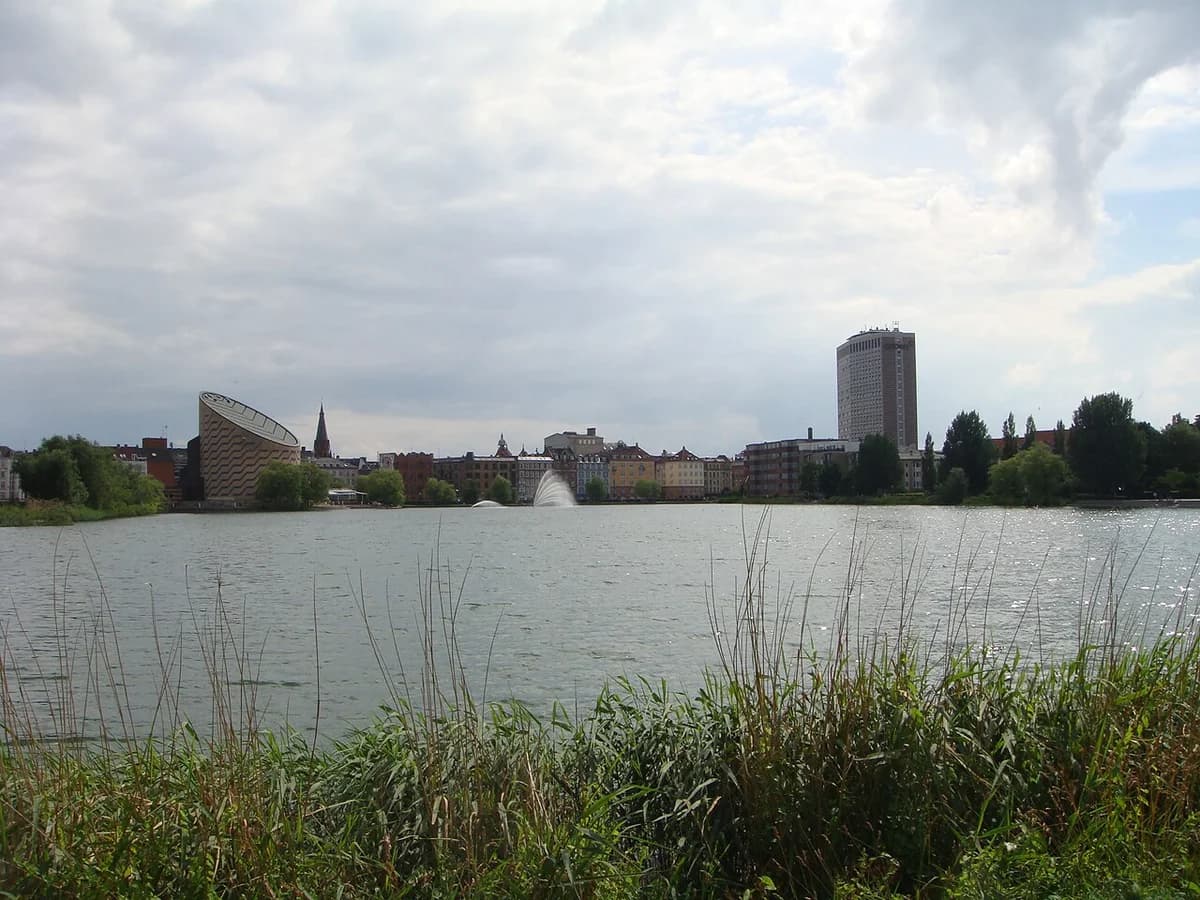 Copenhagen waterfront skyline with the Planetarium on the left and a tall high-rise on the right under cloudy skies.