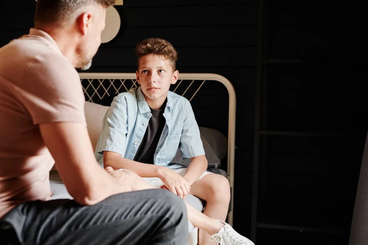 A father talking with his son while sitting indoors.