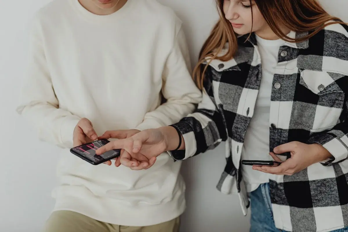 Two teenagers sharing content on smartphones indoors