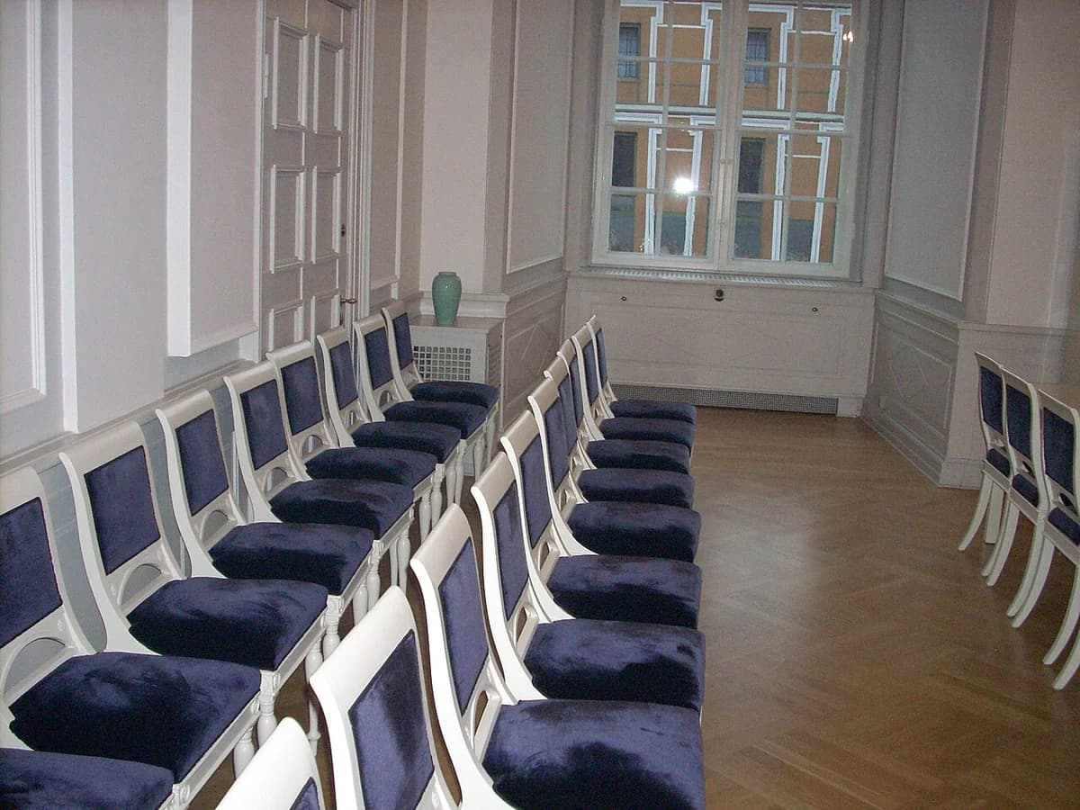 Empty courtroom with white chairs and blue cushions