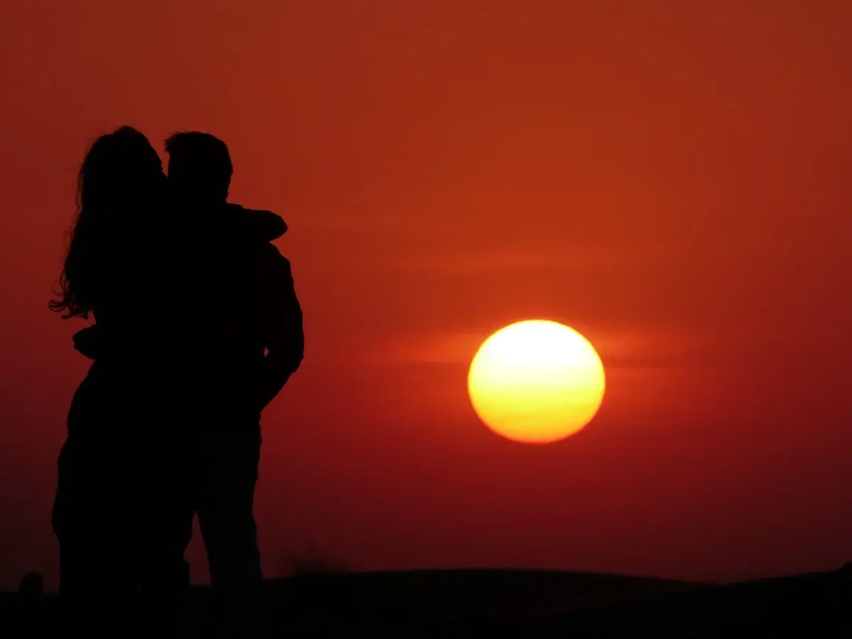 Silhouetted couple embracing at sunset.