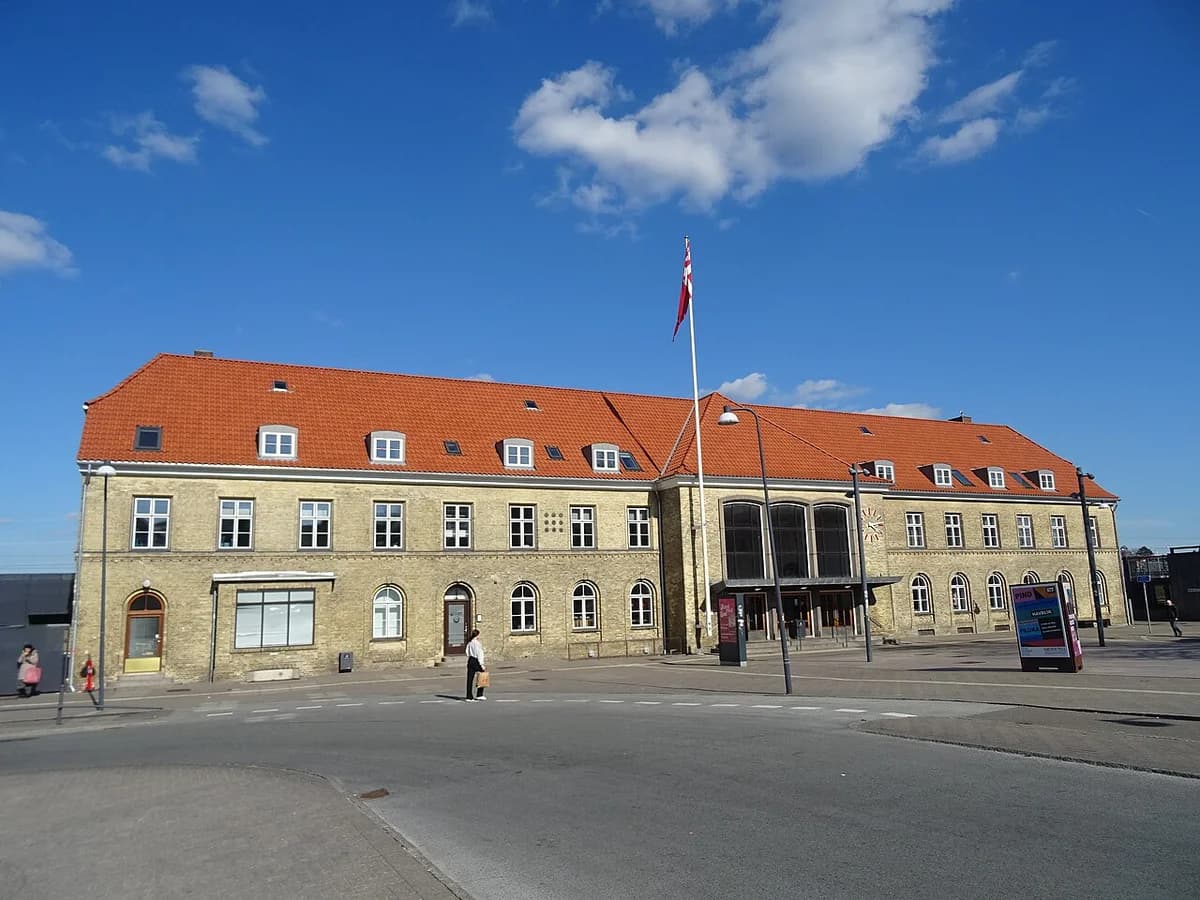 A station building in Næstved, Denmark, with a Danish flag in front.