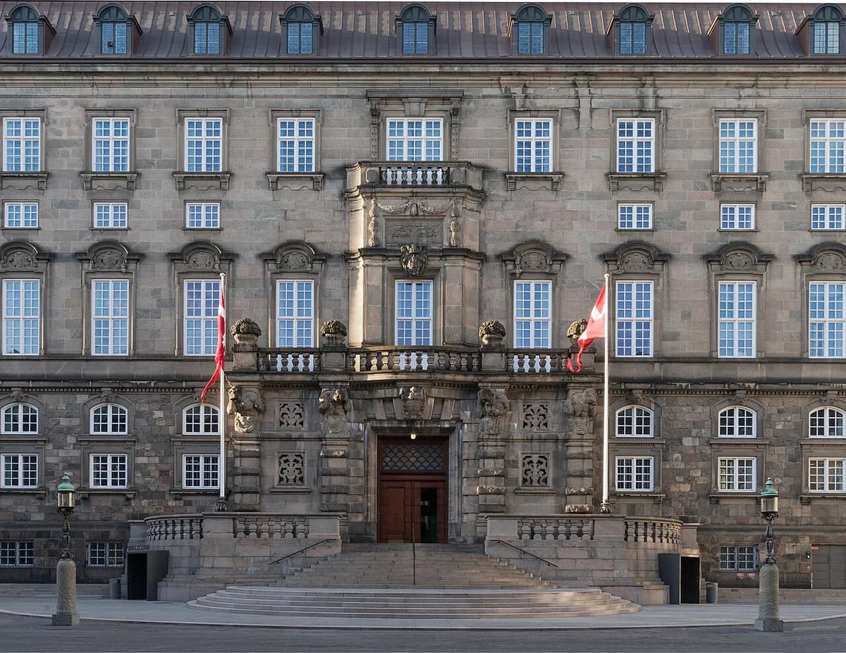 Front facade and entrance of Christiansborg Palace with Danish flags.