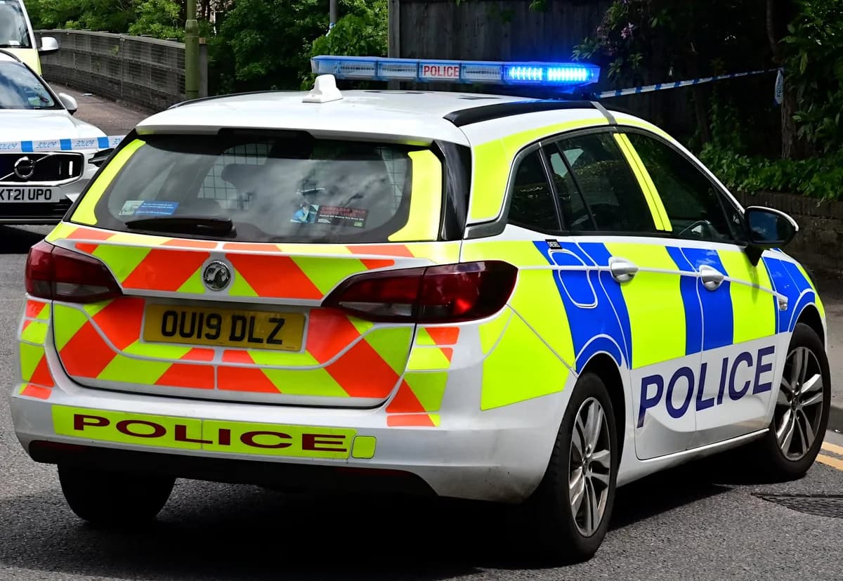 Rear view of British police car with flashing blue lights on road