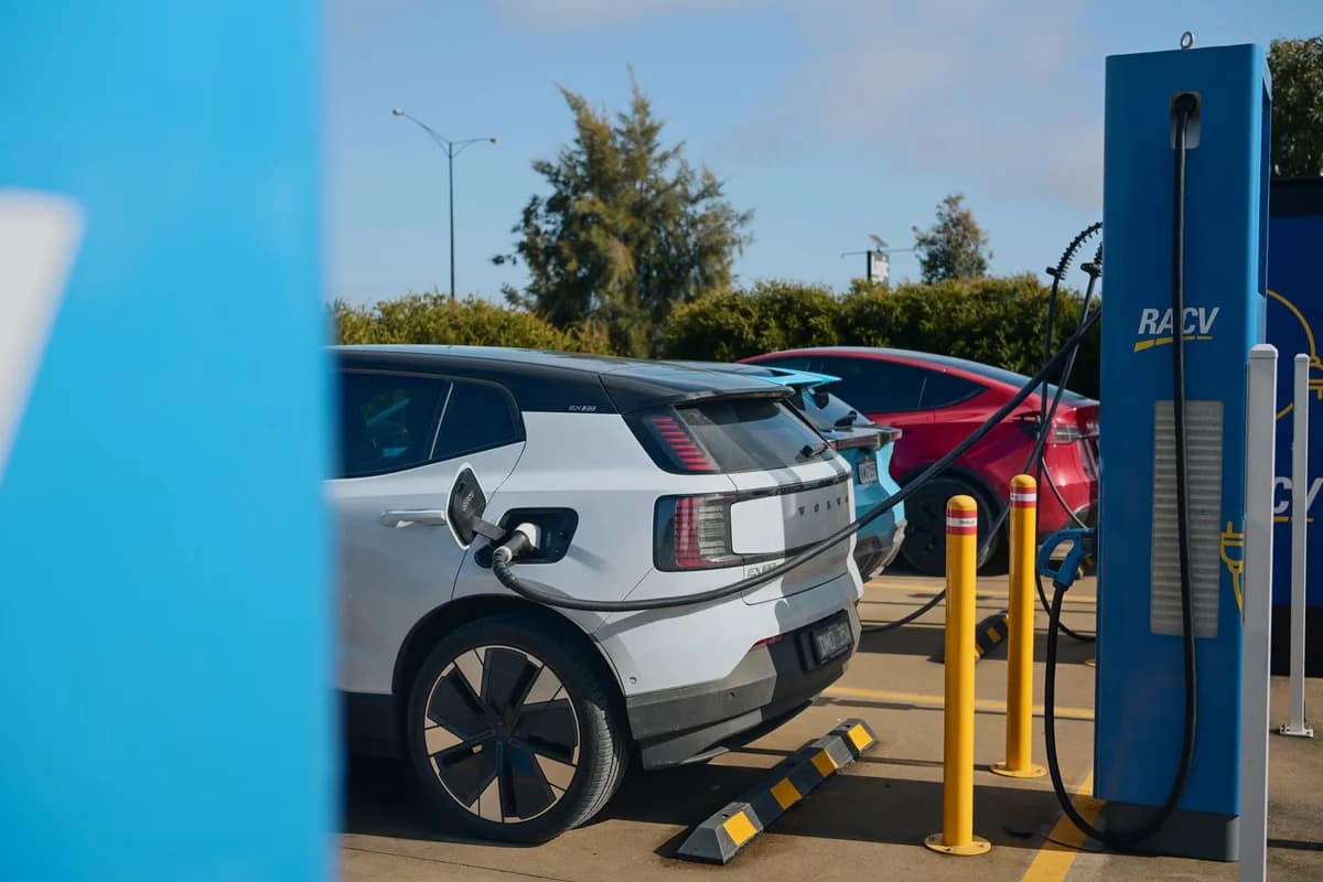 Electric cars plugged into an RACV charging station at a roadside charging area.