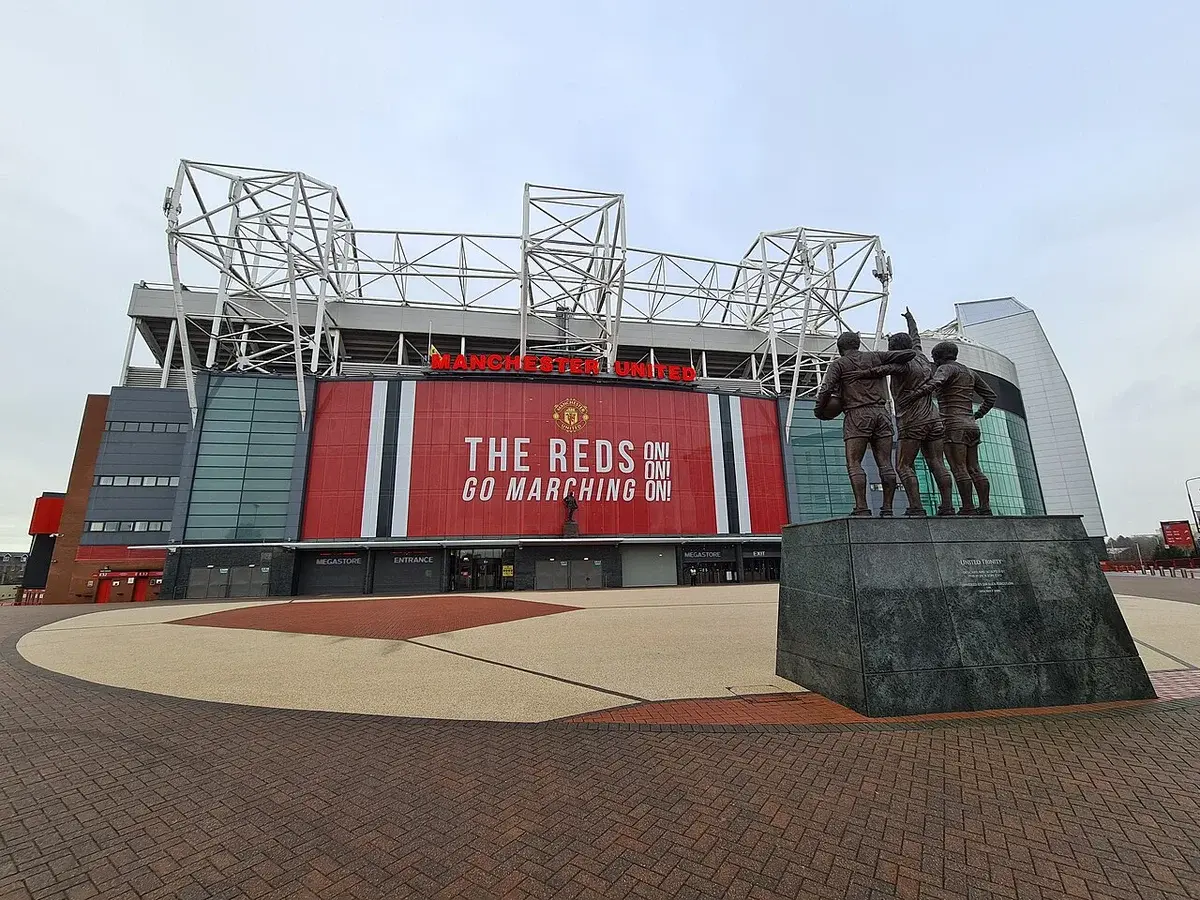 Empty Old Trafford stadium with statue of football players in front