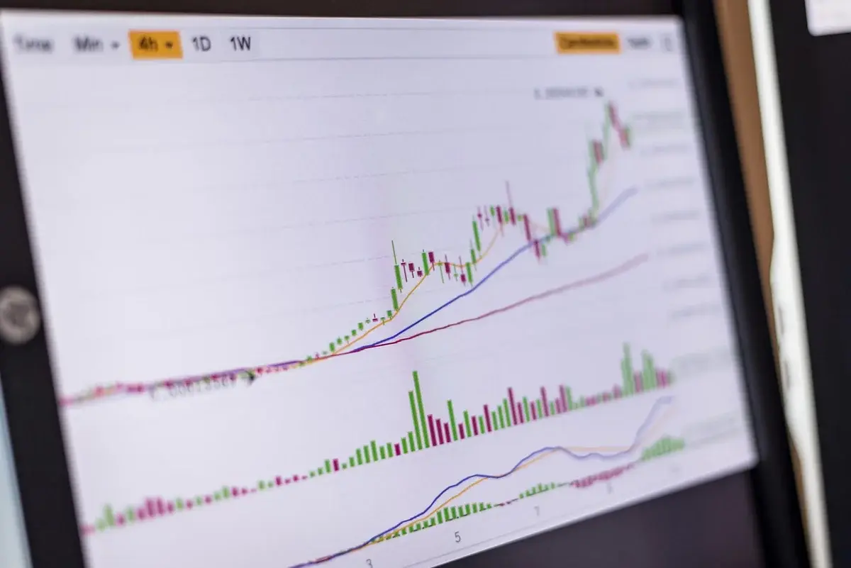 A trading screen shows a stock chart trending upward.