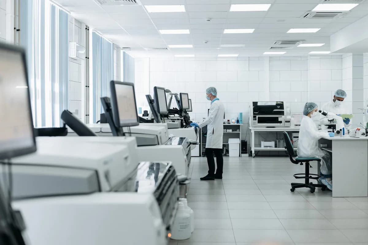 Researchers work in a bright modern medical laboratory with microscopes and computers.