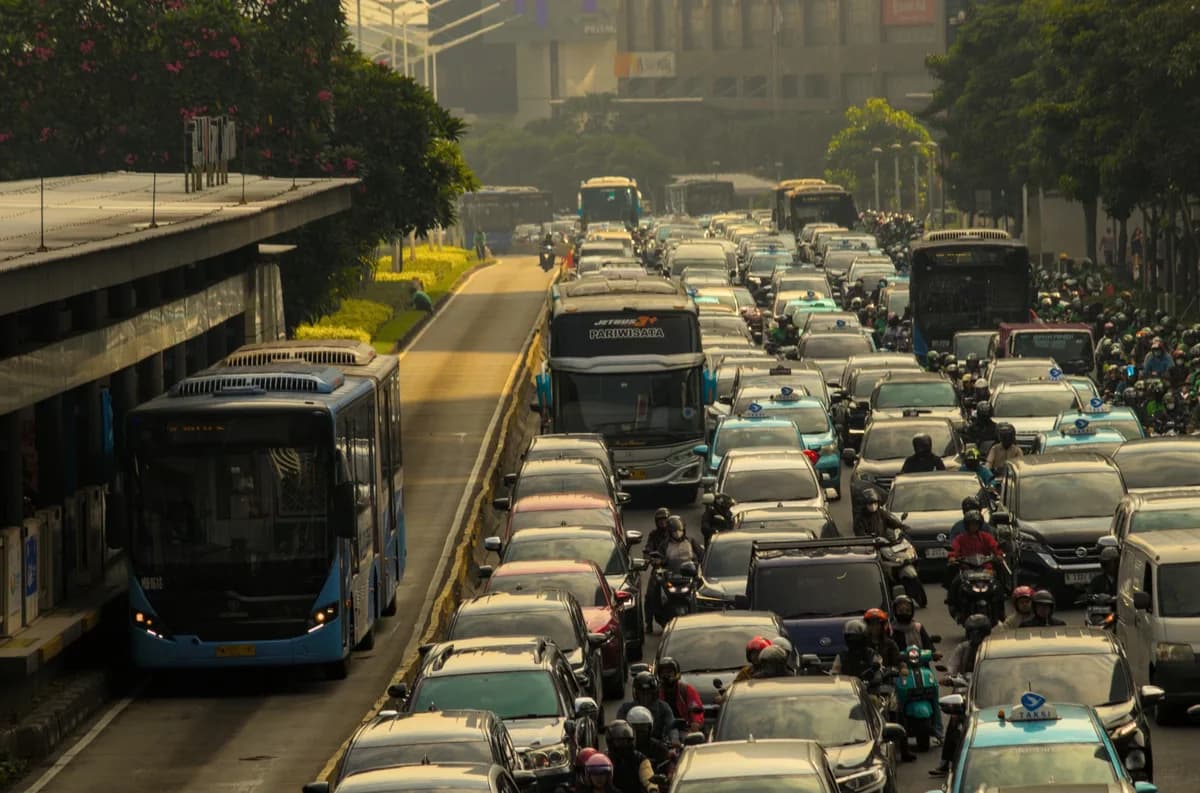 Busy city street filled with cars, buses, and motorcycles in heavy traffic