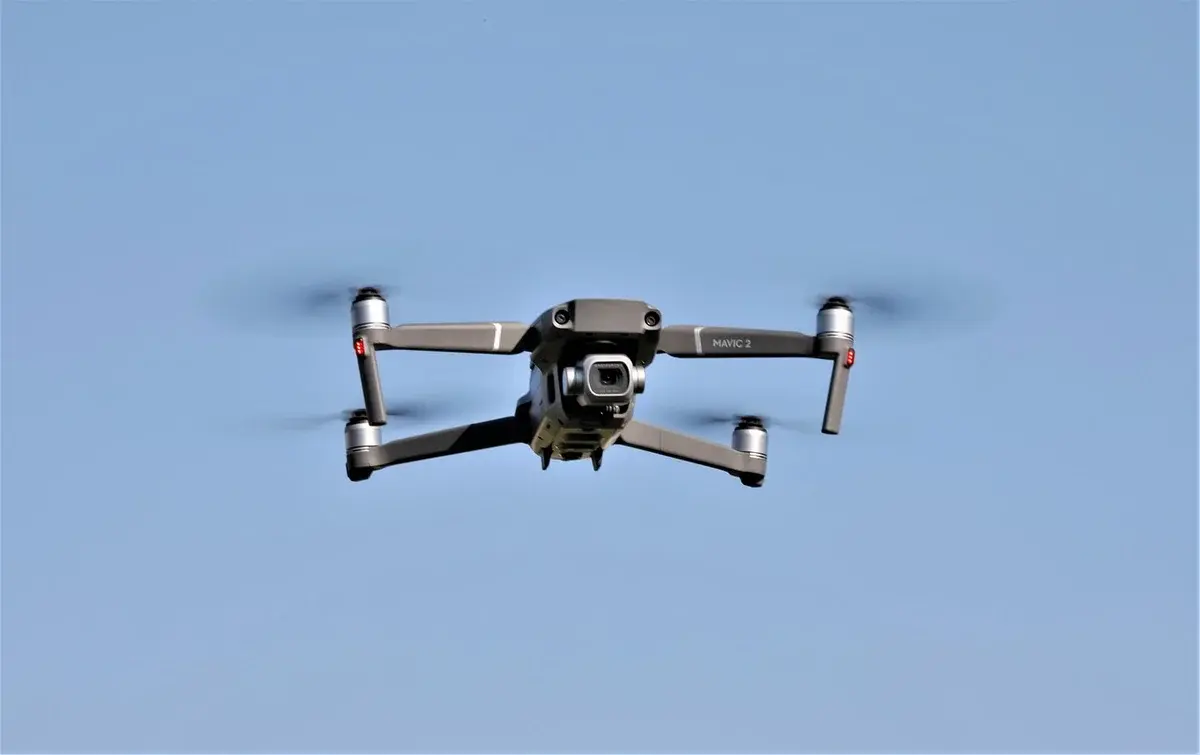 A drone hovering in a blue sky.