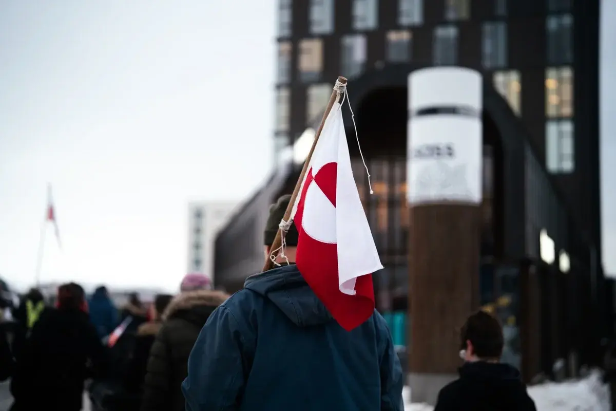 Person holding Greenlandic flag at a protest in Nuuk