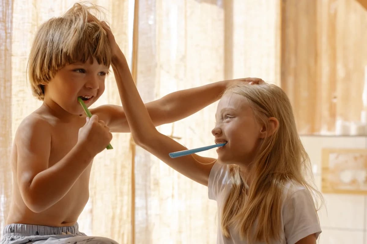 Two children brushing their teeth together in a bright bathroom