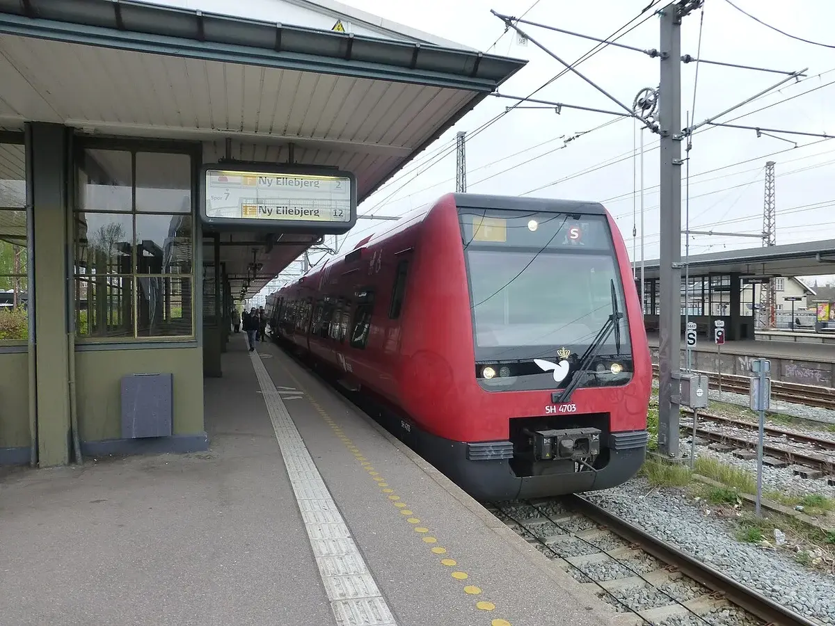 A red commuter train at a railway platform.