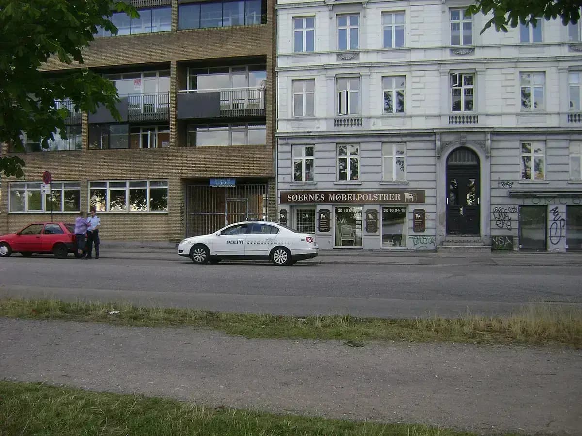 Danish police officers and stopped red car with police vehicle nearby