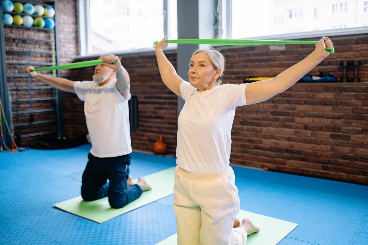 An older couple exercising with resistance bands in a gym.