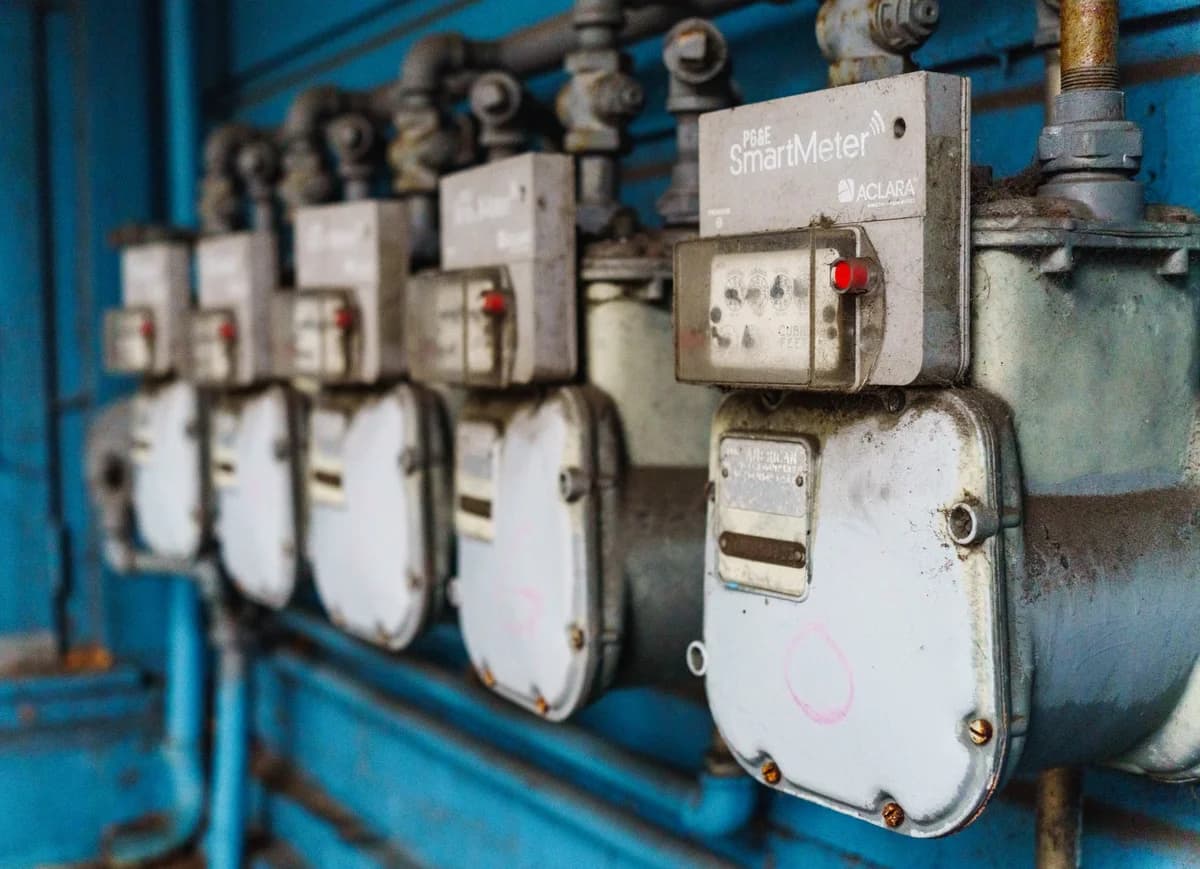 A row of smart electricity meters mounted on a blue industrial wall.