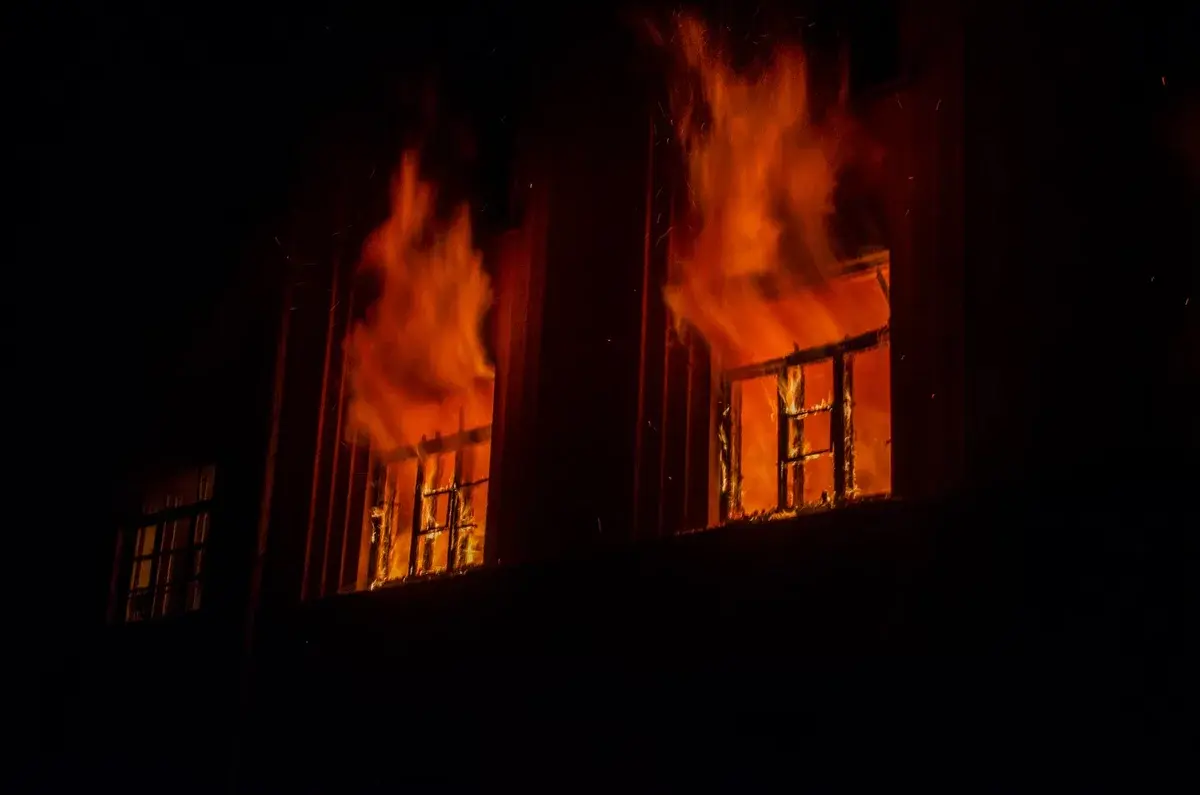 A building on fire at night with flames coming from the windows.