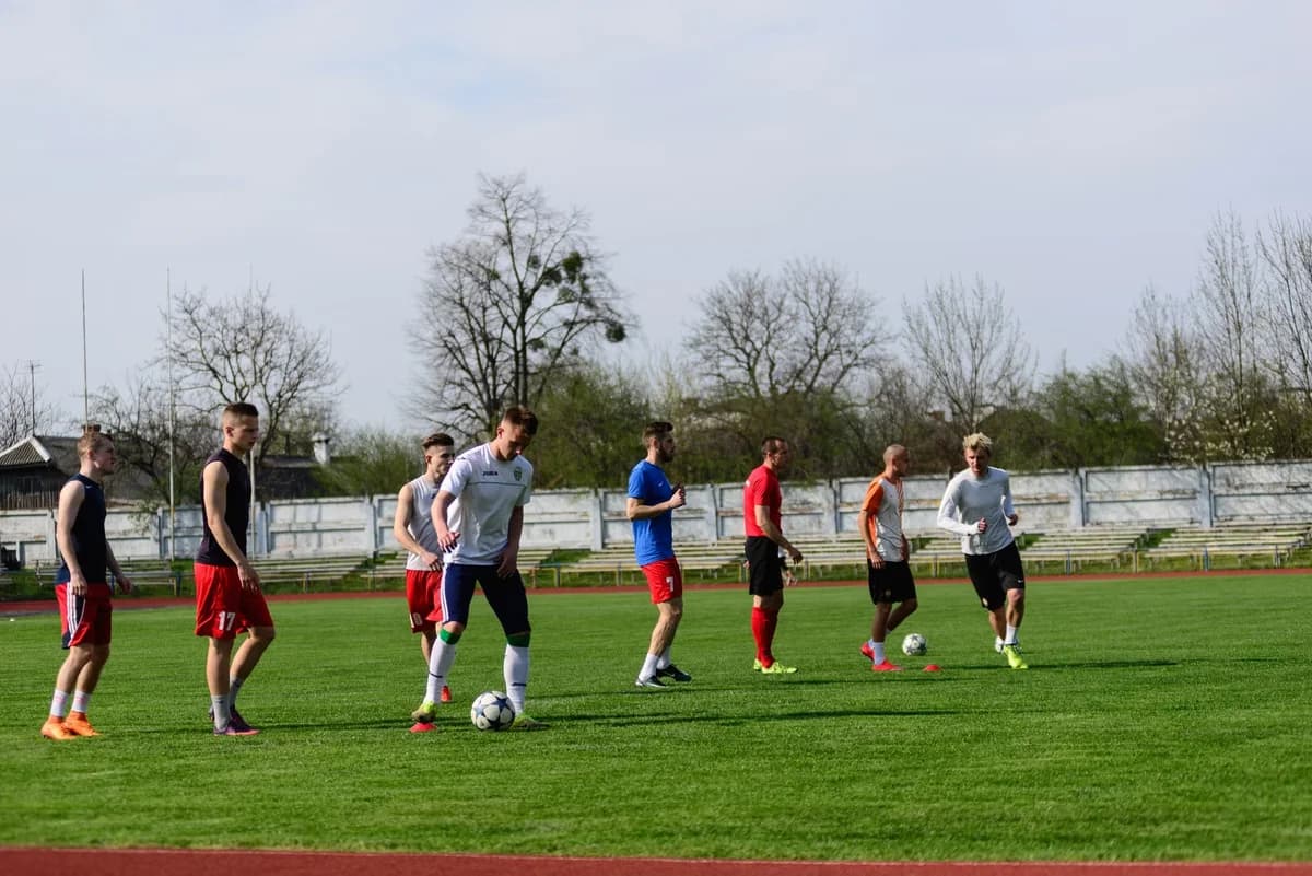 young men playing soccer on green field