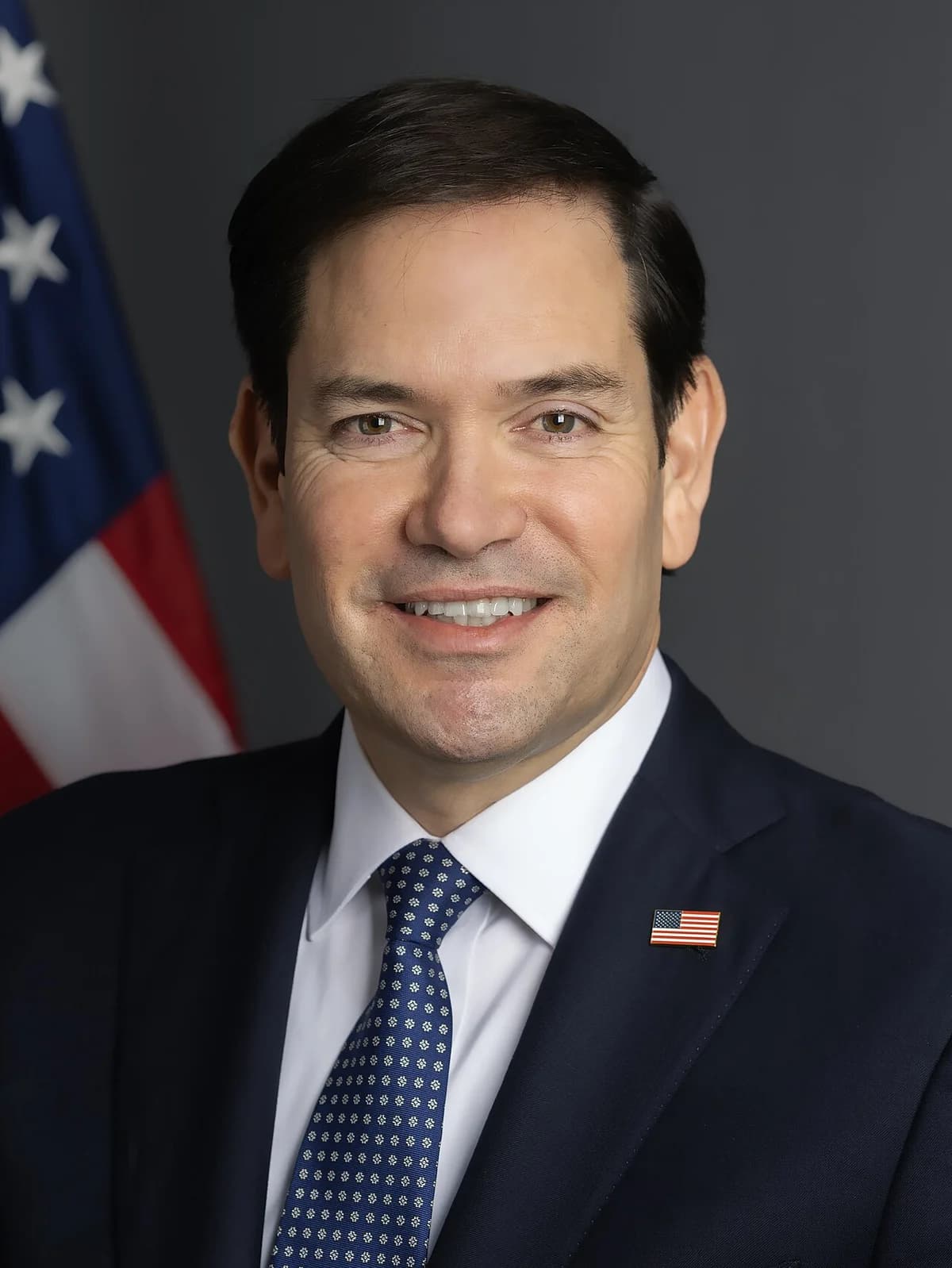 Official portrait of Marco Rubio with a U.S. flag behind him.