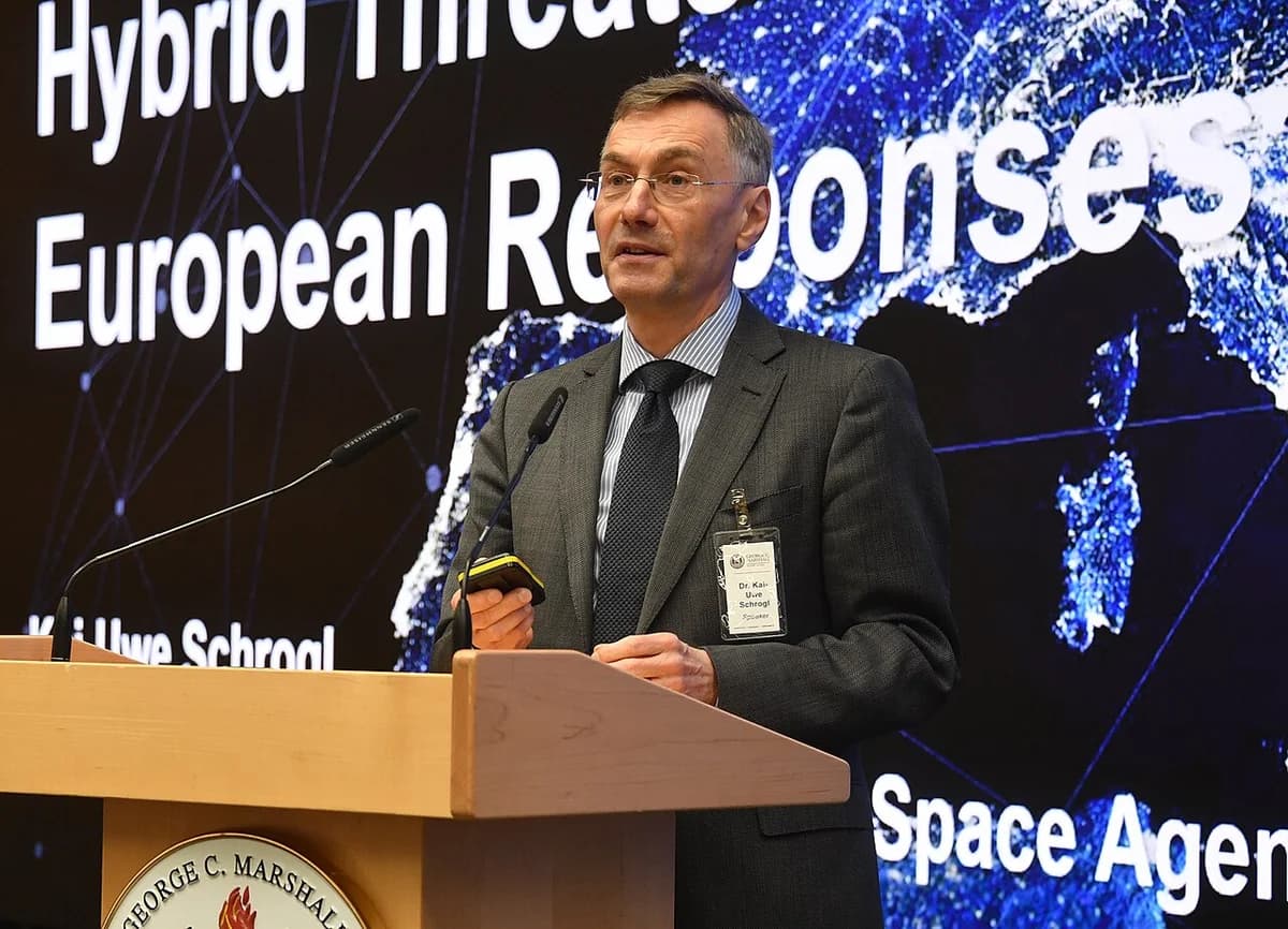 A man speaks at a podium in front of a screen about hybrid threats and European responses.