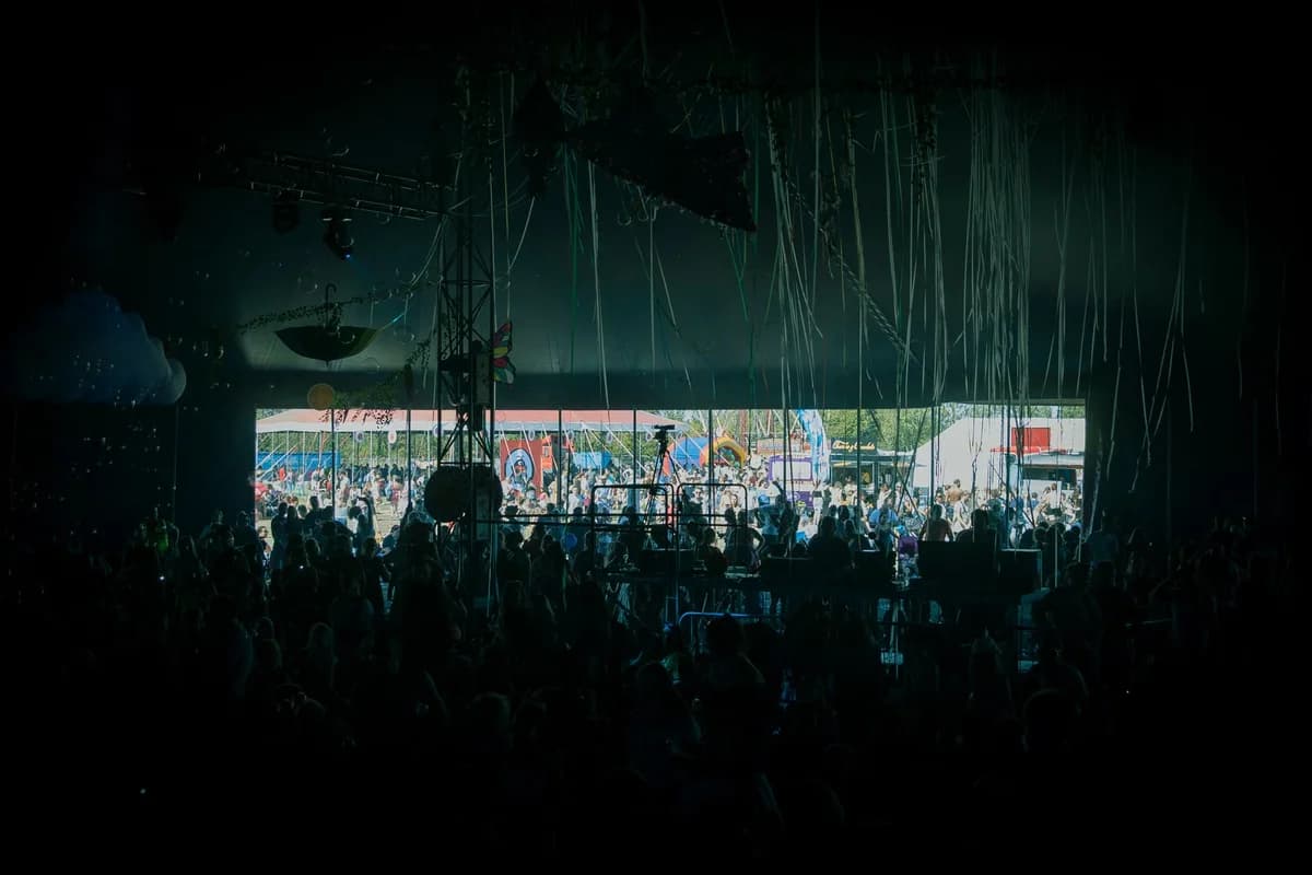 crowd visible through a dark tent opening at an outdoor festival