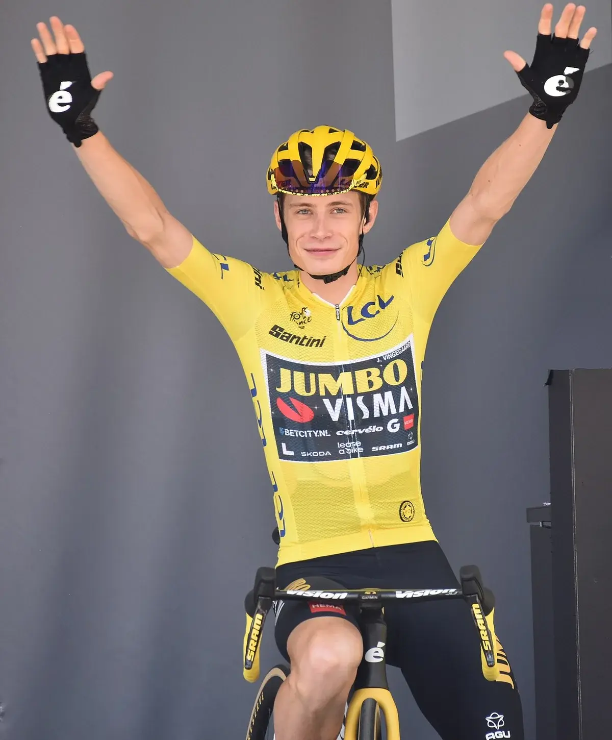 Jonas Vingegaard in yellow jersey raising arms in victory on bike