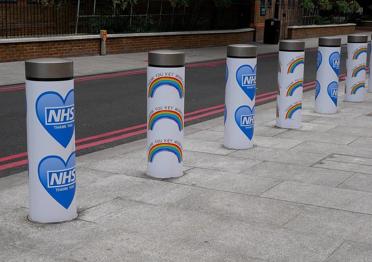 Bollards on a London street decorated with NHS thank-you messages and rainbow designs.