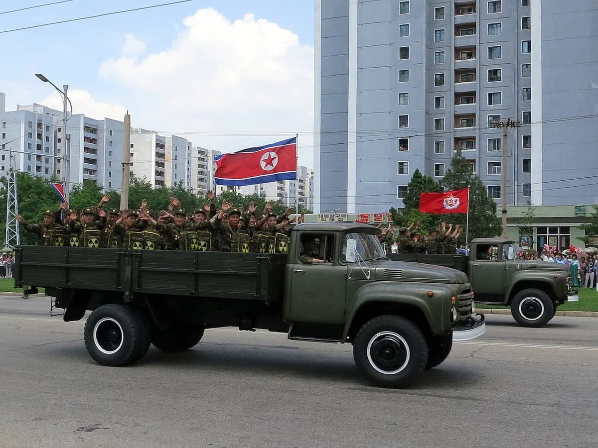 North Korean soldiers ride in parade trucks waving flags during Victory Day celebrations.