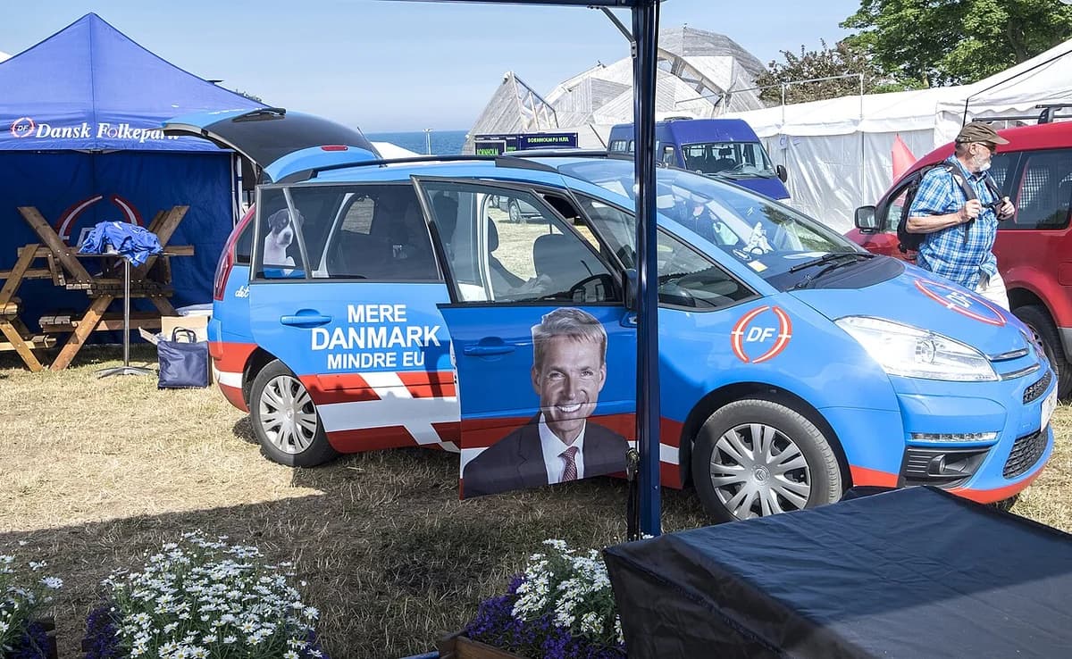 A Danish People's Party booth with a branded car at a political event.