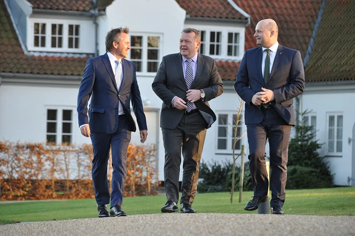 Three Danish politicians walking outside in suits before a coalition announcement.