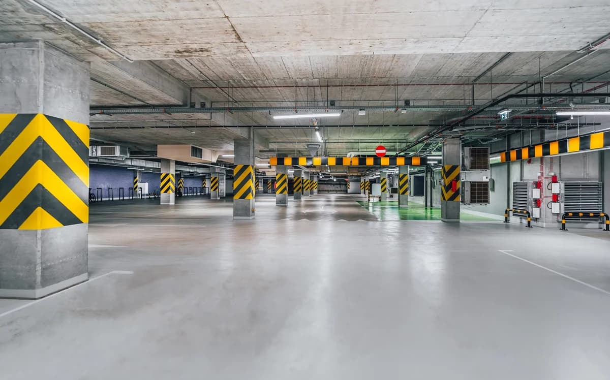 Empty underground parking garage with safety-striped pillars.