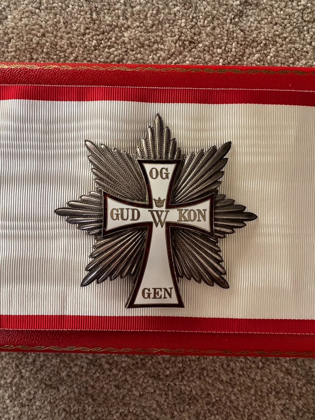 A Danish order insignia with a silver cross on a red-and-white ribbon.