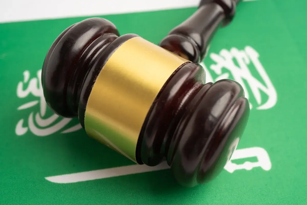 A judge's gavel lying on the Saudi Arabian flag.