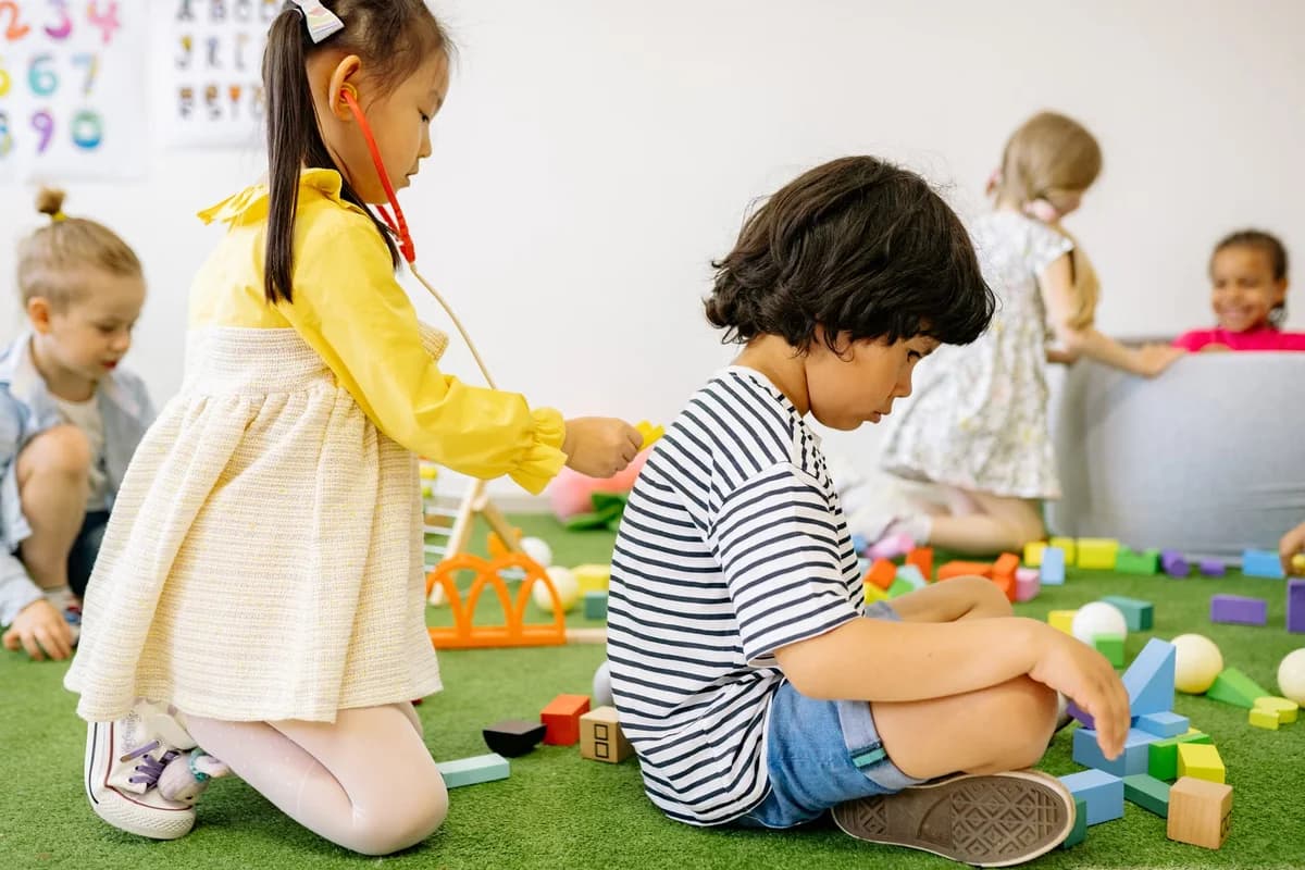 Young children playing with toys in a kindergarten classroom.