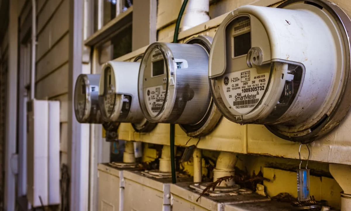 Row of smart electric meters mounted on the outside wall of a residential building.